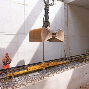 Mitarbeitende positionieren ein Gleisbauteil im Tunnelwerk